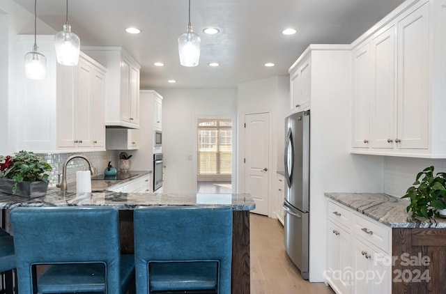 kitchen featuring white cabinets, appliances with stainless steel finishes, kitchen peninsula, and hanging light fixtures