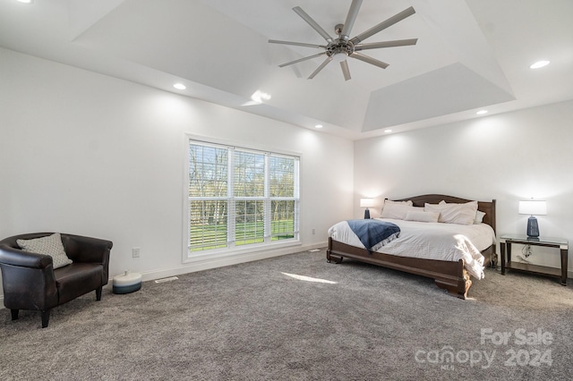 carpeted bedroom with a raised ceiling and ceiling fan