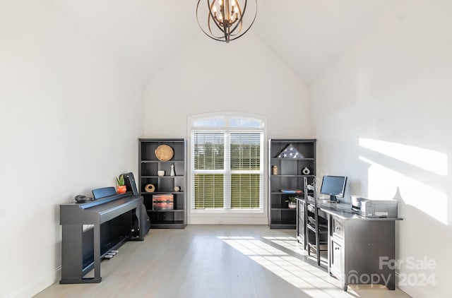 office area with high vaulted ceiling, light hardwood / wood-style floors, and an inviting chandelier