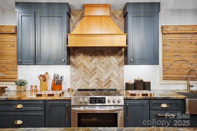 kitchen with stone counters, stainless steel electric stove, backsplash, a sink, and premium range hood