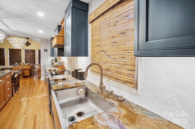 kitchen featuring a chandelier, a sink, light wood-style floors, open floor plan, and custom range hood