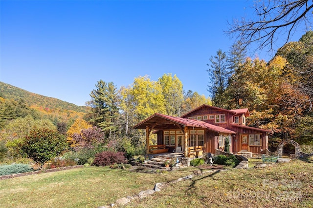 view of front of home featuring a mountain view, covered porch, and a front yard