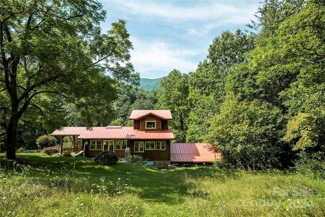 back of house featuring a mountain view and a yard