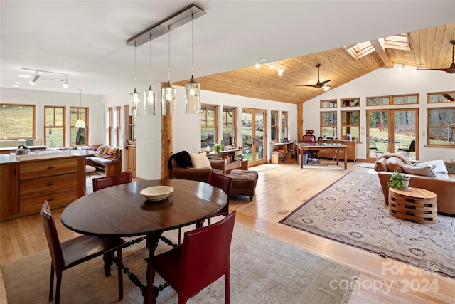 dining space featuring french doors, vaulted ceiling with skylight, ceiling fan, light hardwood / wood-style floors, and wood ceiling