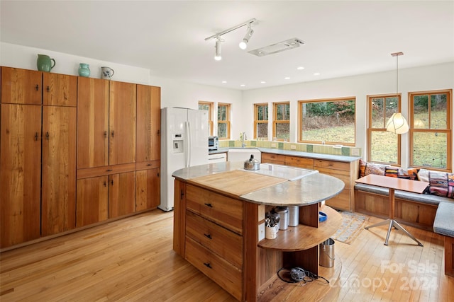 kitchen featuring pendant lighting, light hardwood / wood-style floors, white fridge with ice dispenser, and sink