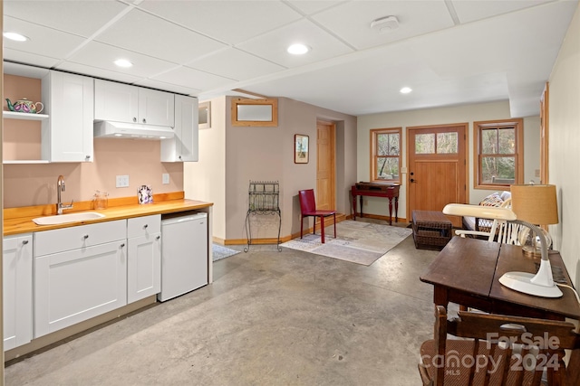 kitchen with a paneled ceiling, white cabinetry, sink, and fridge