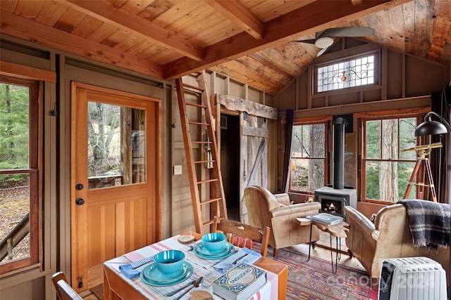 sunroom featuring a wood stove, plenty of natural light, wooden ceiling, and vaulted ceiling with beams