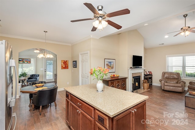 kitchen featuring stainless steel refrigerator with ice dispenser, ceiling fan with notable chandelier, hardwood / wood-style flooring, and a kitchen island