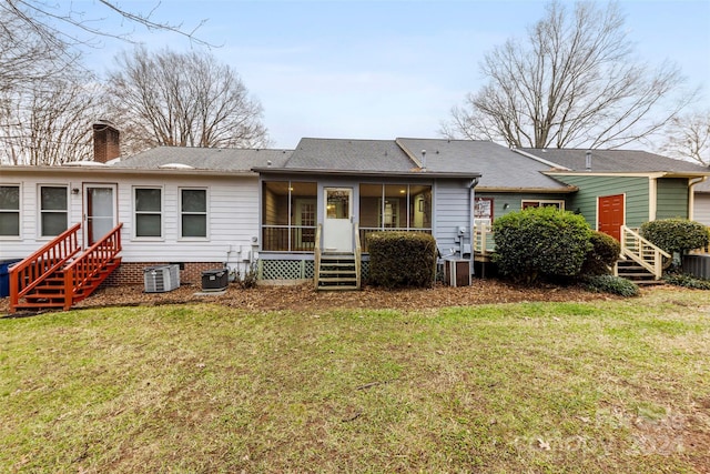 back of house featuring a sunroom, central AC unit, and a lawn