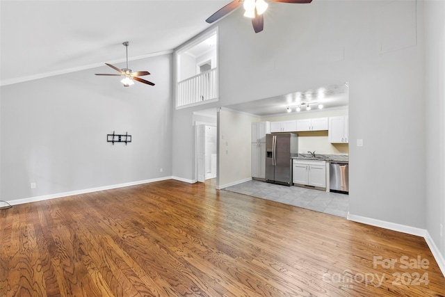 unfurnished living room featuring ceiling fan, sink, high vaulted ceiling, and light hardwood / wood-style flooring