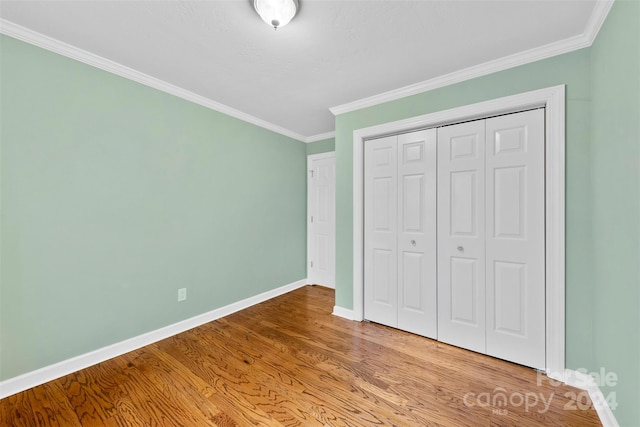 unfurnished bedroom featuring crown molding, a closet, and hardwood / wood-style flooring