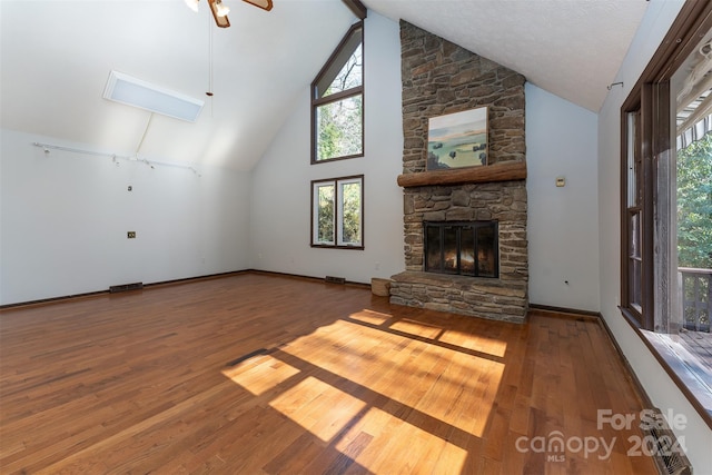 unfurnished living room featuring a fireplace, a textured ceiling, hardwood / wood-style flooring, and high vaulted ceiling