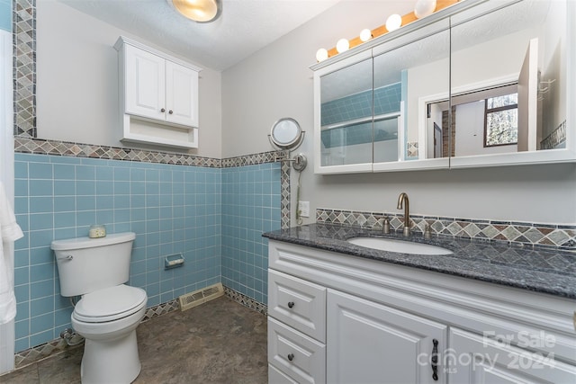 bathroom featuring vanity, toilet, a textured ceiling, tile walls, and walk in shower