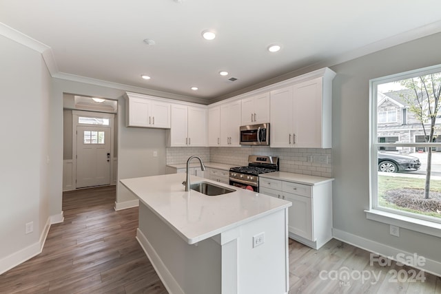 kitchen featuring light wood-type flooring, stainless steel appliances, sink, a center island with sink, and white cabinetry