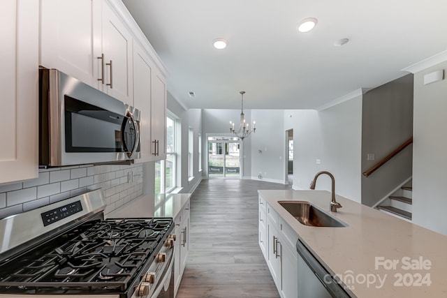 kitchen with white cabinets, sink, appliances with stainless steel finishes, and light hardwood / wood-style flooring