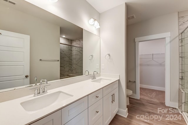 bathroom with toilet, vanity, a shower with shower door, and hardwood / wood-style flooring