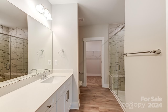 bathroom featuring a shower with shower door, toilet, wood-type flooring, and vanity