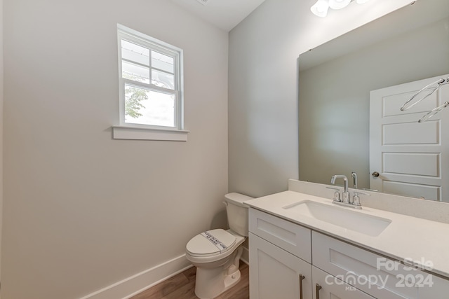 bathroom with hardwood / wood-style flooring, vanity, and toilet