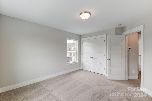 unfurnished bedroom featuring light colored carpet and a closet