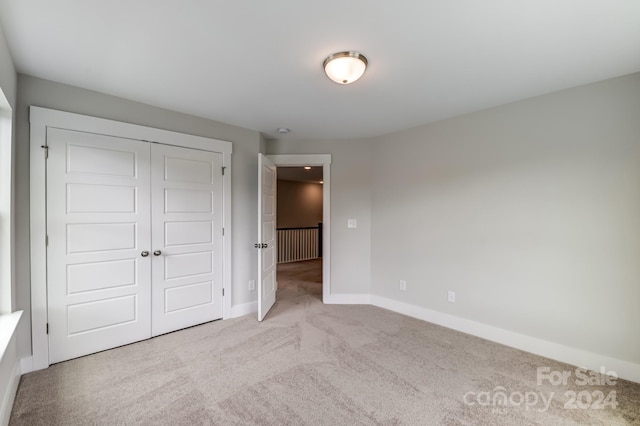 unfurnished bedroom with light colored carpet and a closet