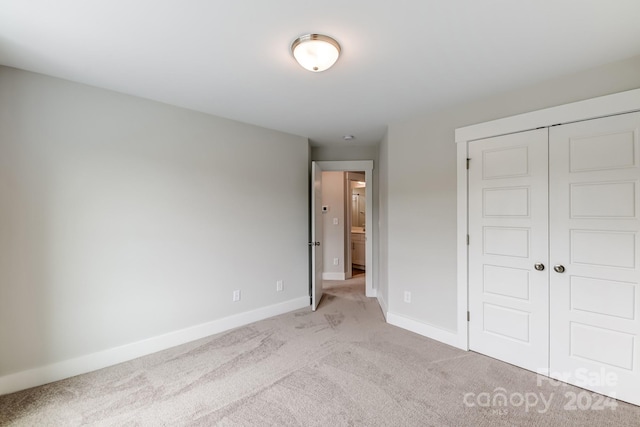 unfurnished bedroom with light carpet and a closet