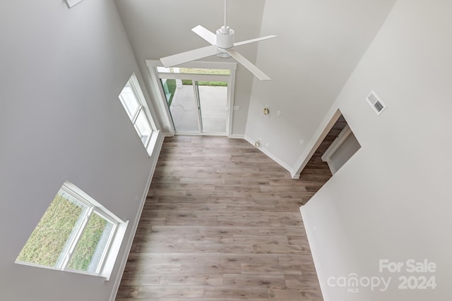 interior space with a high ceiling, ceiling fan, and wood-type flooring