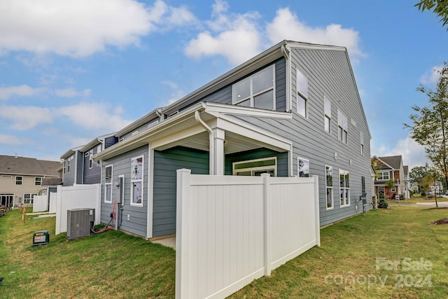 view of side of property featuring a yard and central AC unit