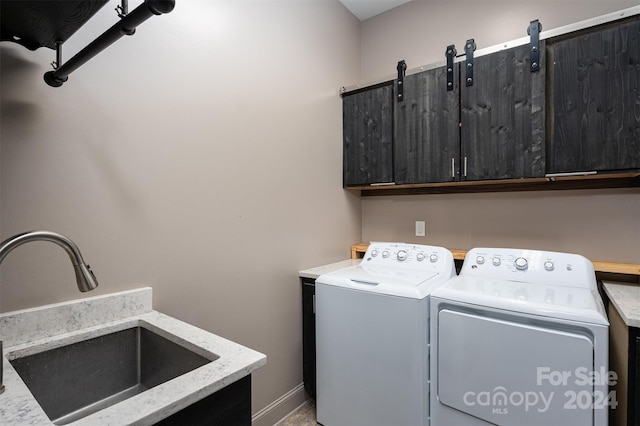 clothes washing area with washer and clothes dryer, cabinets, and sink