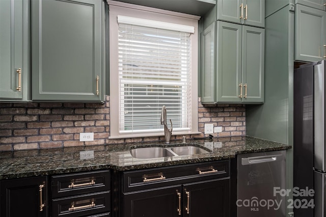 kitchen featuring appliances with stainless steel finishes, backsplash, dark stone counters, and sink