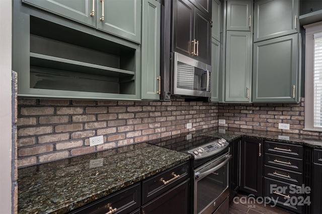 kitchen with a wealth of natural light, dark stone countertops, appliances with stainless steel finishes, and tasteful backsplash