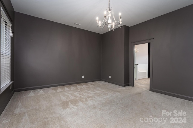 unfurnished room with a notable chandelier and light carpet