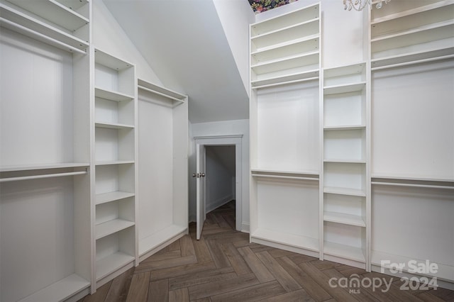 spacious closet featuring dark parquet floors and an inviting chandelier