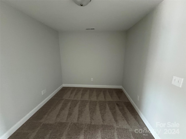 unfurnished room featuring dark colored carpet