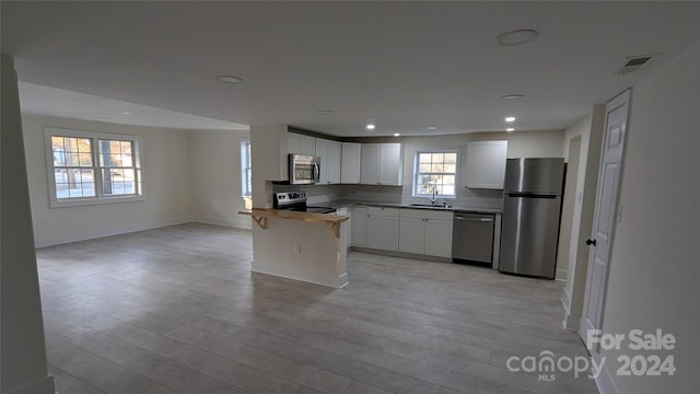 kitchen with white cabinetry, light hardwood / wood-style flooring, wooden counters, and appliances with stainless steel finishes