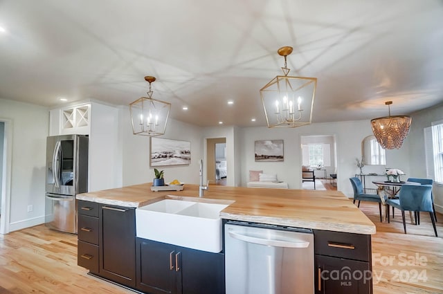 kitchen featuring pendant lighting, sink, stainless steel appliances, and light hardwood / wood-style floors