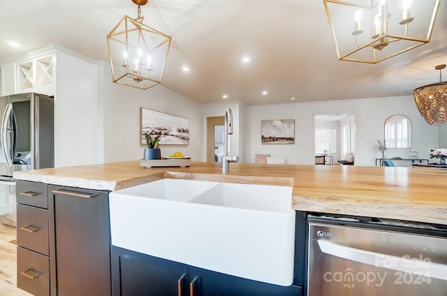 kitchen featuring light stone countertops, sink, stainless steel appliances, pendant lighting, and light hardwood / wood-style floors