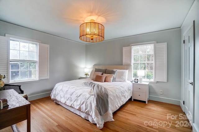 bedroom with light hardwood / wood-style flooring, multiple windows, and crown molding