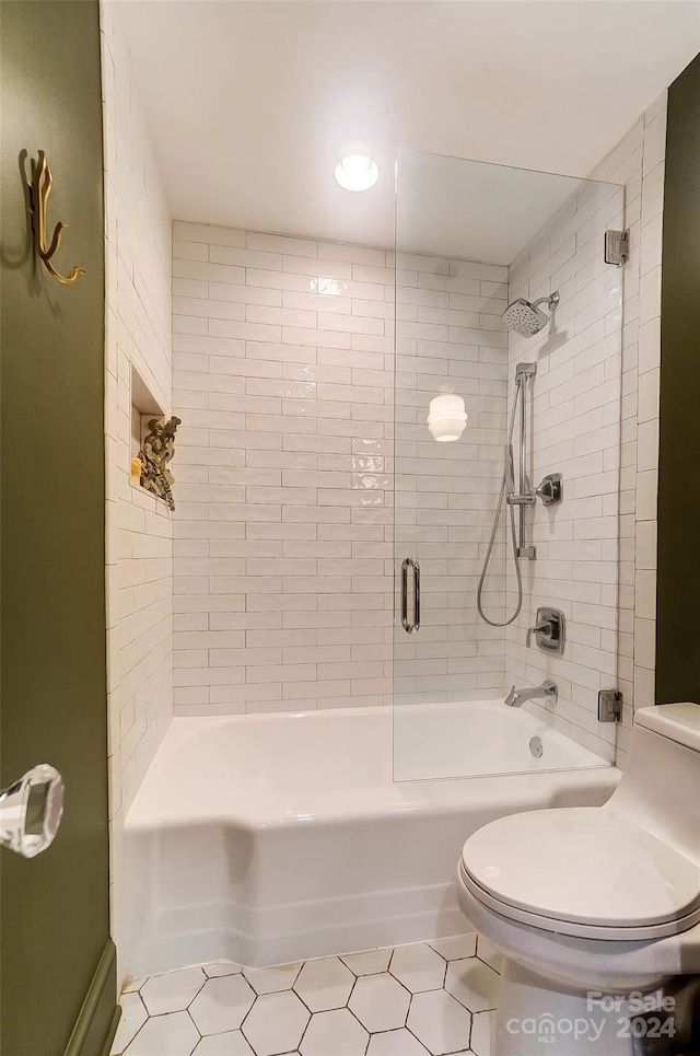 bathroom with tile patterned flooring, tiled shower / bath combo, and toilet