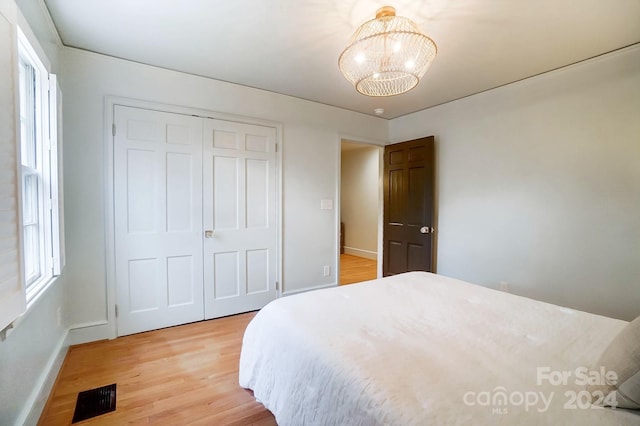 bedroom featuring hardwood / wood-style floors, a notable chandelier, and a closet