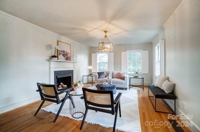 living room featuring hardwood / wood-style floors, ornamental molding, a fireplace, and an inviting chandelier