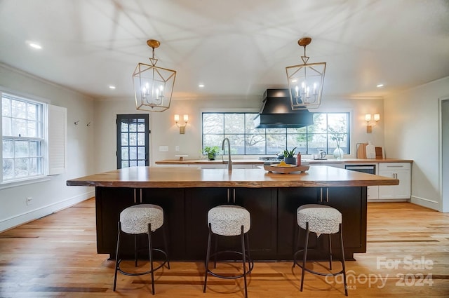 kitchen featuring ventilation hood, an inviting chandelier, light hardwood / wood-style flooring, white cabinets, and hanging light fixtures