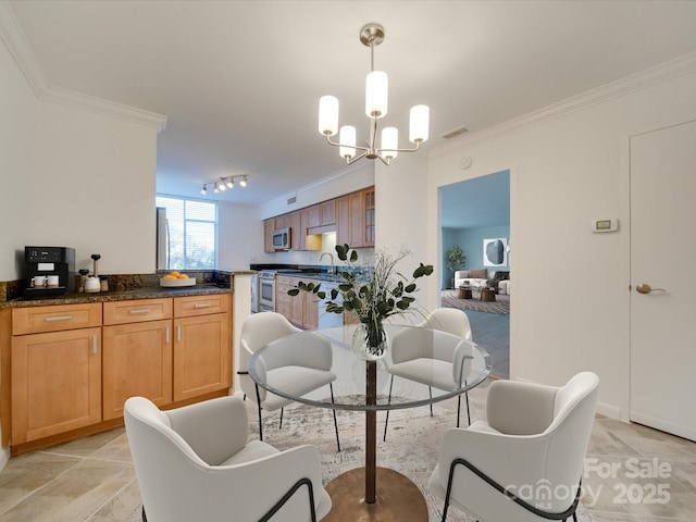 dining area featuring ornamental molding, track lighting, visible vents, and an inviting chandelier