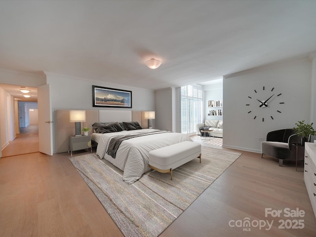 bedroom with ornamental molding, light wood-type flooring, and baseboards