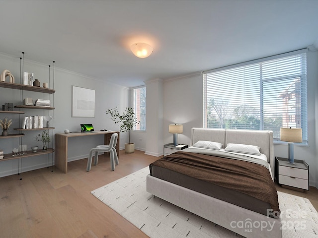 bedroom with light wood-style floors, baseboards, and crown molding