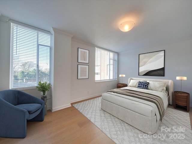 bedroom with baseboards, crown molding, multiple windows, and light wood-style floors