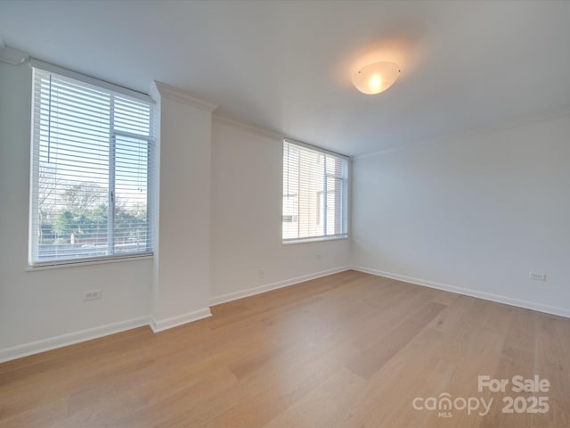 empty room featuring baseboards, light wood-type flooring, and a healthy amount of sunlight