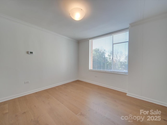 spare room with crown molding, light wood-style flooring, and baseboards