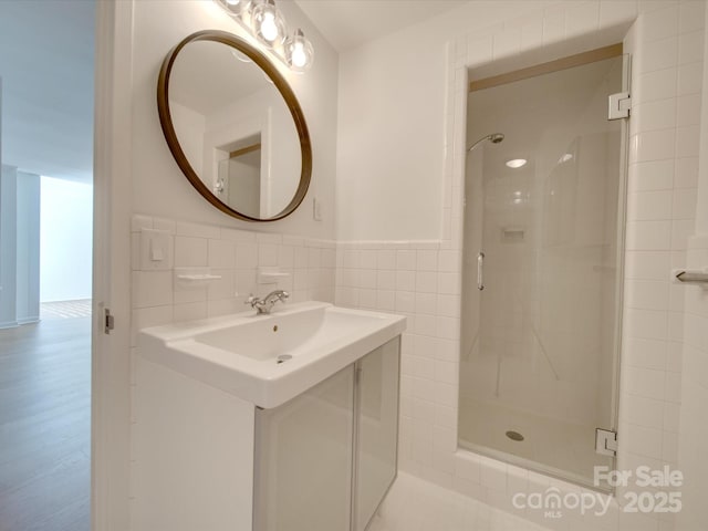 bathroom featuring tile walls, wainscoting, and a shower stall