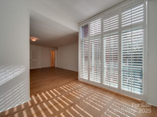 empty room with brick wall and wood finished floors