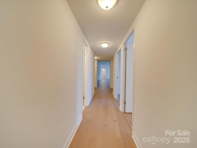 hall with light wood-style flooring and baseboards